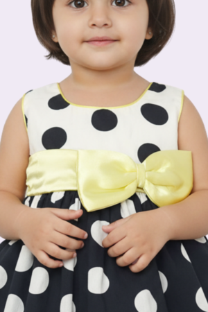 Detalle frontal del vestido de niña lunares negro y blanco con moño amarillo removible